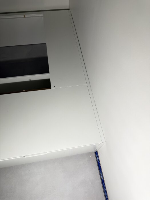 Hemmagjord sängtäcklist av gamla hyllplan med synliga skruvar och lite ojämna kanter, placerad i ett barnrum.