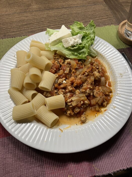 Tallrik med pasta, köttfärssås, salladsblad och fetaost.