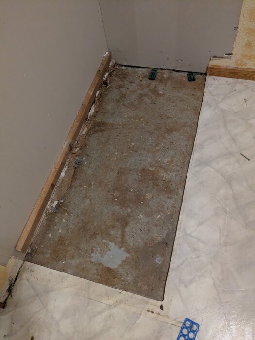 Öppen sektion av golv med synlig betongplatta, omgiven av väggar och en golvkant, efter borttagning av köksbänk i renoverat hus från 1971.