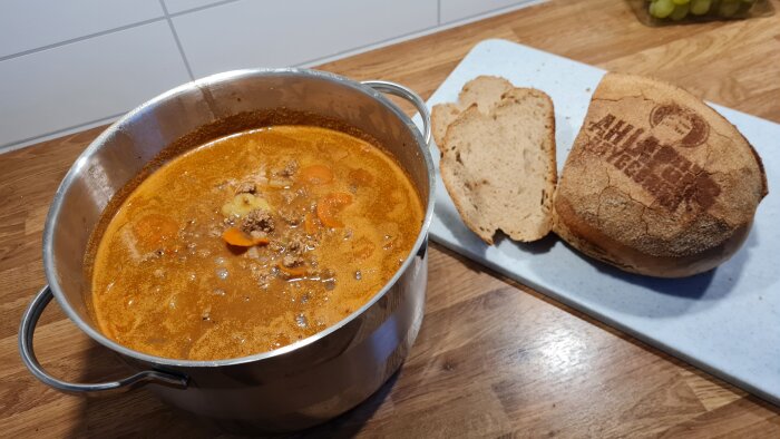 Gryta med soppa och skivor av surdegsbröd på en skärbräda, redo att serveras på en höstdag.
