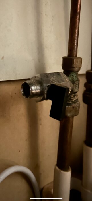 Närbild av en anslutning för tappventil i metall, med kopparrör och svart handtag, för inkoppling av diskmaskin.