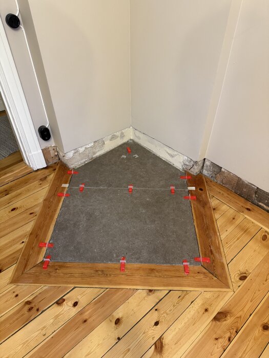 Klinkergolv är på plats i en hörna av rummet, avgränsat med trälist. Röda avståndsclips synliga, väntar på fogning.