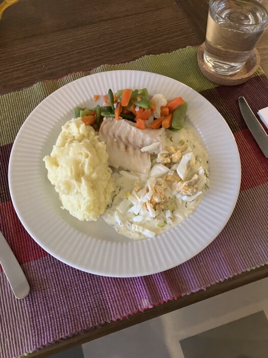 Tallrik med kokt torsk, potatismos, grönsaker och sås av purjolök, grädde, citron, dill och hackat ägg.