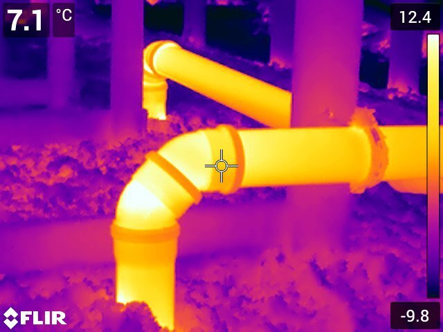 Värmekamerabild av rör i kallvind visar olika temperaturer, vilket kan tyda på värmeförlust och påverka smältningen av snö på taket.