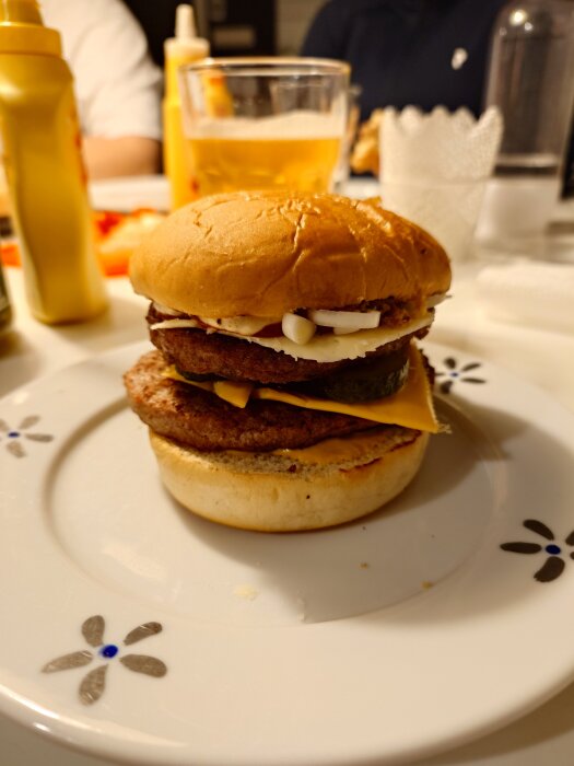 Hamburgare med prästost och skivad lök på en vit tallrik; gul senapsflaska och glas i bakgrunden på ett diskussionsforum.