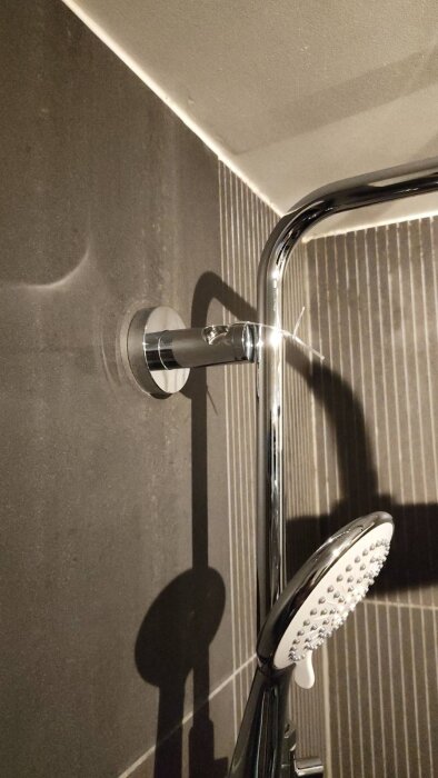 Nyinstallationen av en billig duschblandare med takdusch mot en mörk kakelvägg, beskriven som temporär.