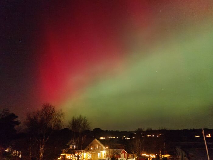 Norrsken över en fastighet i Bohuslän med röda och gröna nyanser på natthimlen.