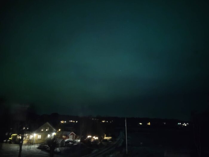 Norrsken över hus och landskap i Bohuslän på kvällen.
