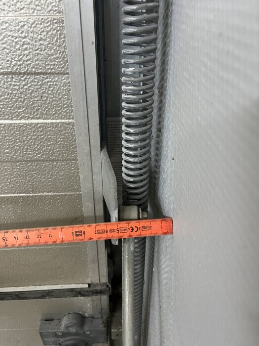 Måttband mäter avståndet mellan garageportsfjäder och vägg.