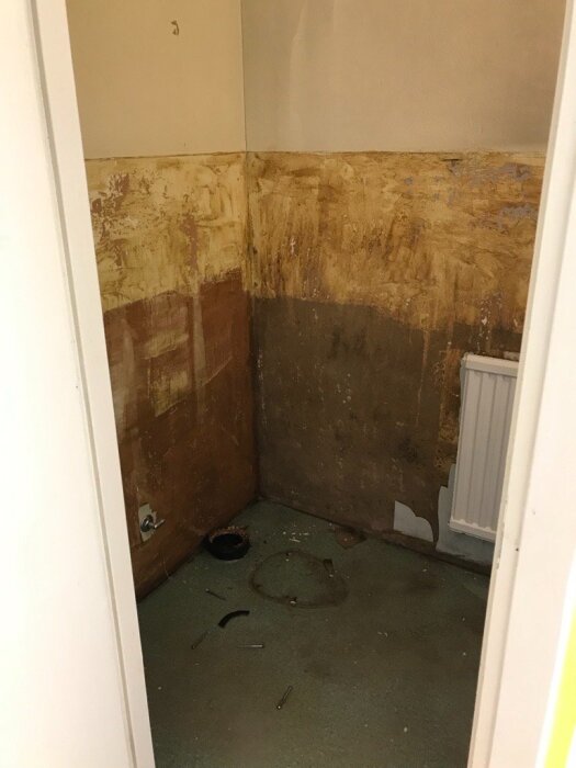 Toalett under renovering med exponerade väggar och golv. Verktyg och rördelar ligger på golvet, redo för arbete.