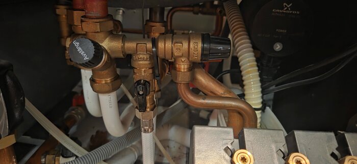 VVS-installation med rör och ventiler, visande vredet på en Nibe F750 frånluftsvärmepump för påfyllning av värmesystemet.