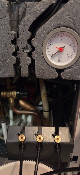 Manometer visar ~0.5 bar tryck i en Nibe F750 värmepump. Omgivande rör och komponenter synliga för handpåfyllning av värmesystemet.
