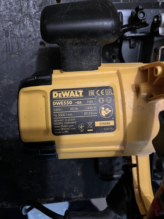 Gul Dewalt cirkelsåg DWE550 med märkplatta som visar specifikationer, inklusive effekt 1200W och varvtal 5500/min, på en arbetsbänk.
