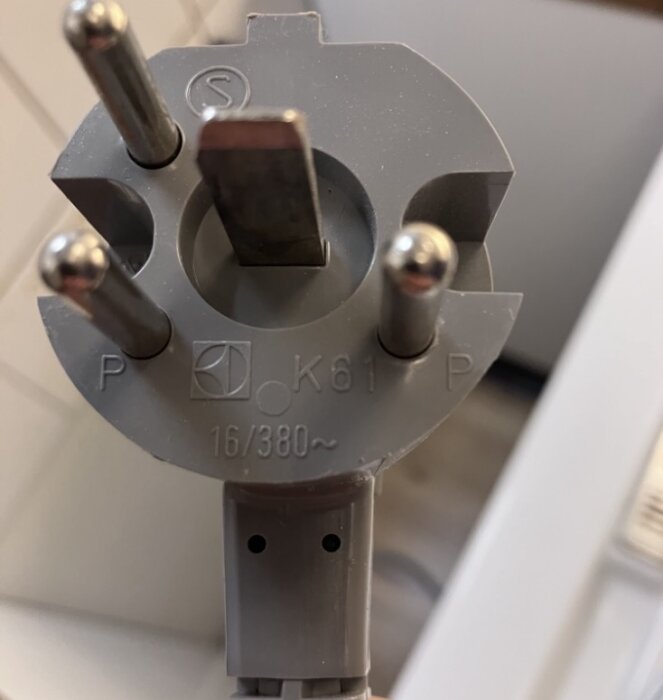 Grå elkontakt med flera stift märkta 16/380 volt, används för att ansluta en spis.