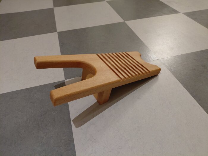 Stövelknekt i rödbok med linoljebehandling, placerad på golv med schackrutigt mönster, designad med avlång tapp istället för skruv.