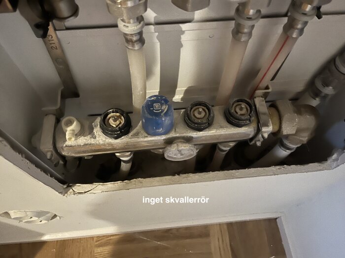 Rörinstallation bakom en vägg med flera anslutningar och märkning "inget skvallerrör".