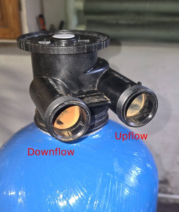 Vattenfilterbehållare med två anslutningar märkta "Downflow" och "Upflow" på en blå tank.
