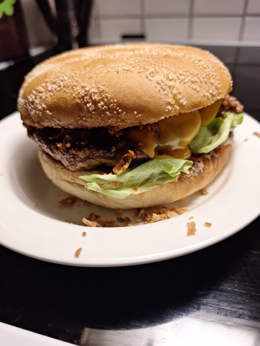 Hamburgare med dressing, sallad, ost och rostad lök på en tallrik.