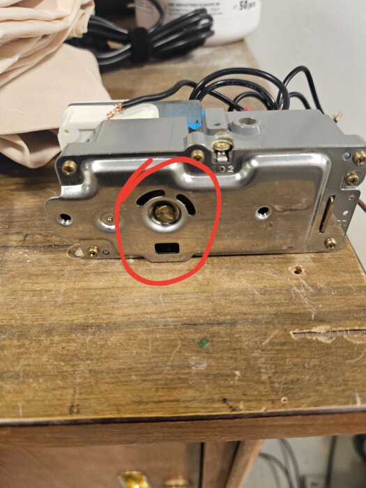 Urets manövreringsaxel på en avfrostningstimer i närbild, markerad med en röd cirkel på ett träbord.