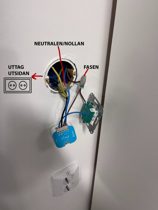 Öppen elinstallation med Plejd CTR-01 kopplad till kablar märkta fas och nolledare, nära en Schneider strömbrytare och vägguttag.