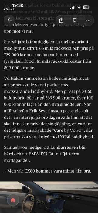 Interiör av en bil med ratt på vänster sida, två digitala skärmar på instrumentbrädan och havsutsikt genom vindrutan.