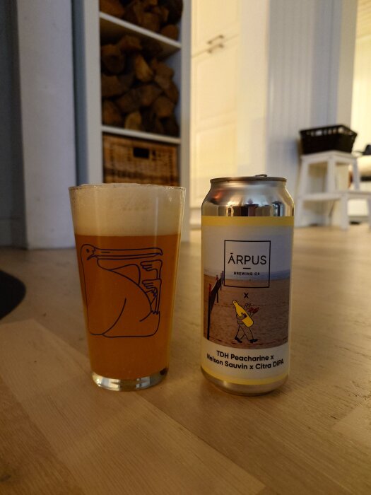 En ölburk från Ārpus Brewing och ett glas med skummande öl på ett golv, vedförvaring syns i bakgrunden.