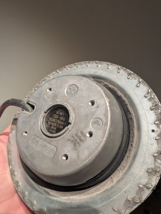 Närbild på en ventilationsfläkt från Östberg, visar fläktens metallhölje och dess bakre del med kabelanslutning.