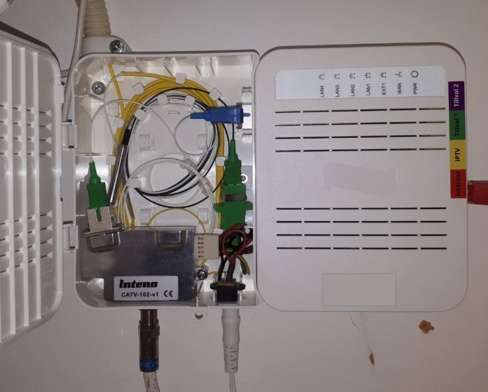 CATV-modul fäst på väggen med anslutna kabelfibrer för kabel-tv och internetanslutning.