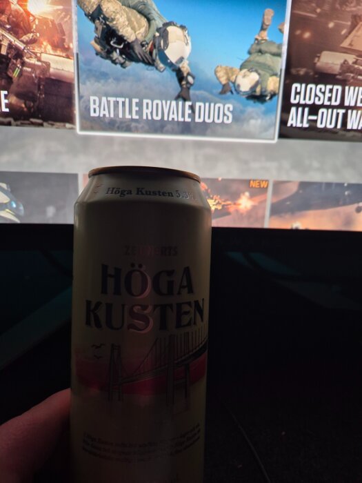 Burk med Höga Kusten-öl hålls framför en datorskärm som visar spelmenyn för "Battle Royale Duos".