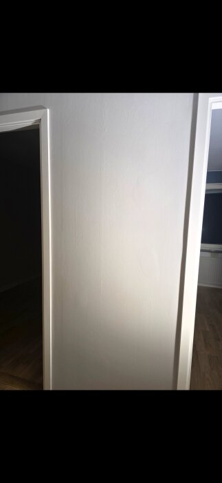 Nymålad vägg med ojämn ytstruktur, observerad av missnöjd kund efter spackling och slipning i lägenhet.