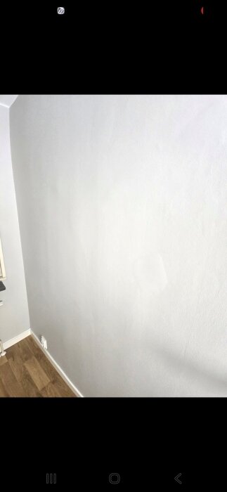 Nymålad vägg i lägenhet med skuggor och fläckar, visar eventuella brister efter slipning och spackling.