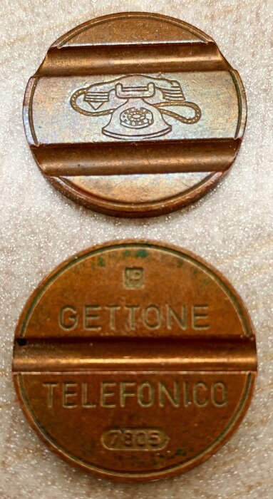 Italienska telefonpoletter i metall med graverad telefon och texten "GETTONE TELEFONICO", designade för att undvika förfalskning.