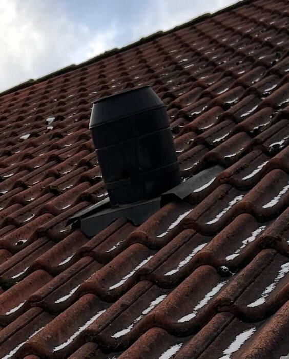 Tak med tegelpannor och en takhuv som sticker upp, potentiellt för ventilationskanal, synlig.