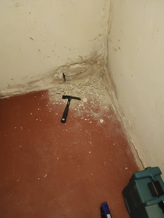 Knackad puts i hörn med exponerat plåtrör och verktyg liggande på golvet.