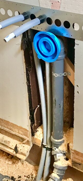 Bild av synliga rör och isolering i en vägg med träram samt en blå plugg i ett nyrenoverat badrum som diskuteras i forumet.