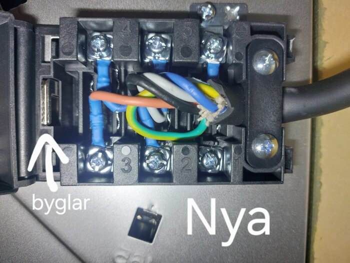Kopplingsdosa med flera färgade kablar anslutna och numrerade skruvplintar, inklusive byglad sektion märkt "Nya".