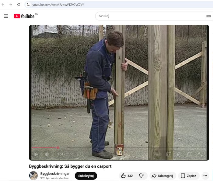 En person i arbetskläder bygger en carport genom att justera en träregel i en stående konstruktion.