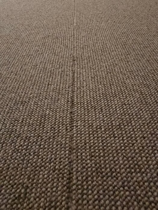 Brun, texturerad heltäckningsmatta med en synlig mittskarv.