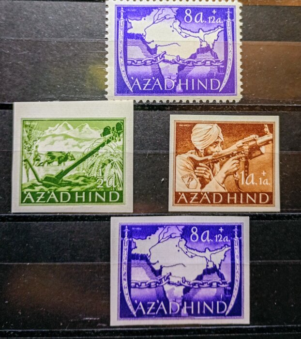 Fyra Azad Hind-frimärken med olika motiv: karta med kedjor, soldat med gevär, jordbruksscen, och karta i lila, grönt, brunt, och lila.