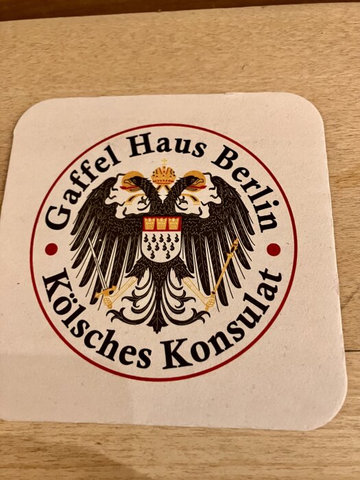 Underlägg med Gaffel Haus Berlin-logo och tysk örn, text "Kölsches Konsulat" skriven runt.