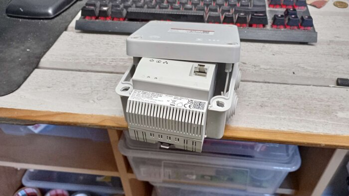 Grå Devolo Magic 2 LAN DINrail adapter på ett skrivbord, framför ett tangentbord, i installationsprocess.