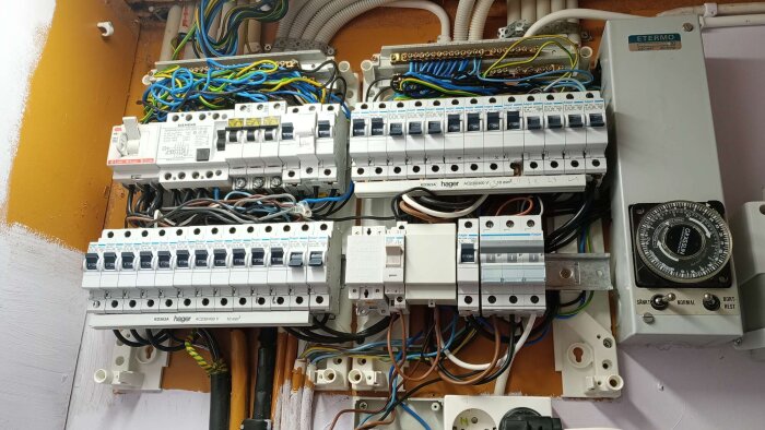 Elcentral med säkringar och ledningar, visar installation och kopplingar i ett hem för att förbättra nätverksanslutning och strömförsörjning mellan hus och garage.