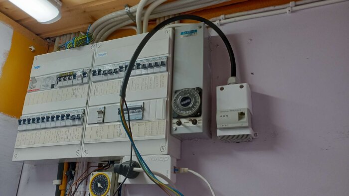 Elskåp med strömbrytare och ledningar, en ETERMO timer och en Devolo Magic LAN adapter monterade på väggen.