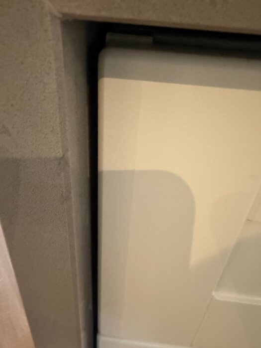 Bilden visar ett nära foto av mellanrummet mellan en stenskiva och ett bänkskåp i en köksö, med skugga på den ljusa ytan.
