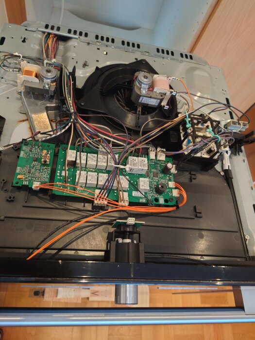Insidan av en ugn med elektroniska delar och kretskort synliga, där två motstånd har bytts ut mot ledare.