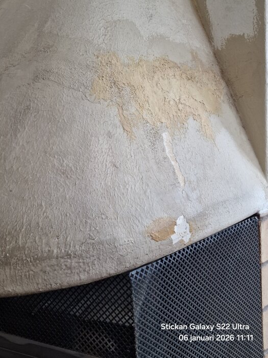 Grå köksspis med kåpa i närbild, visar skadad yta med brännmärken och sprickor.