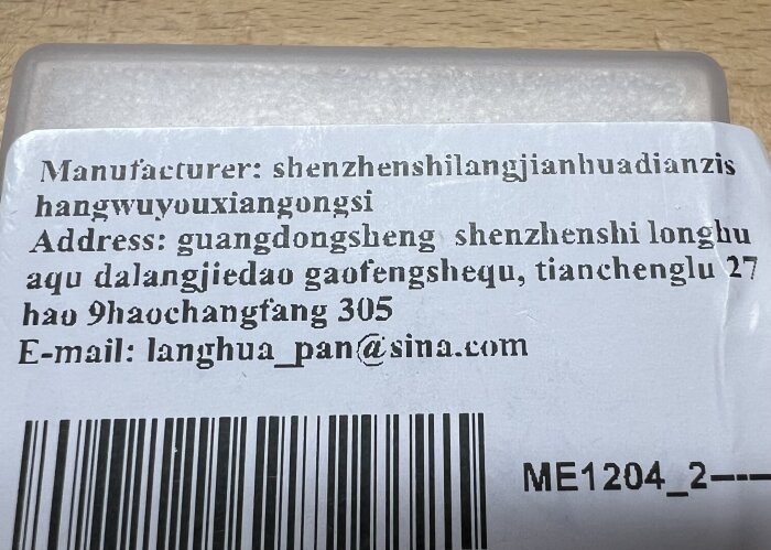 Textetikett med tillverkarens namn och adress i Kina tillsammans med en streckkod.