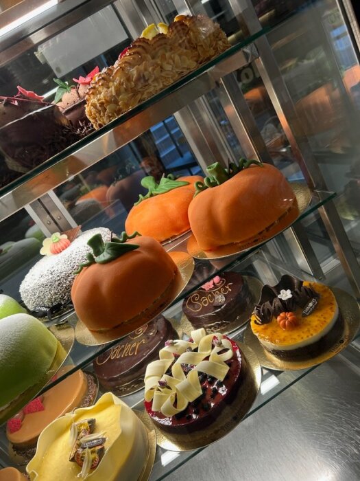 Tårtutbud hos Thimons Konditori i Nässjö med halloween-inspirerade bakverk, bland annat tårtor i pumpaform samt andra dekorerade desserter.