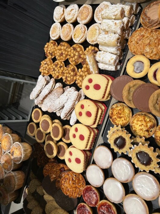 Olika bakverk från Thimons Konditori i Nässjö, inklusive muffins, kakor, och tårtor med glasyr, uppställda på en bricka.