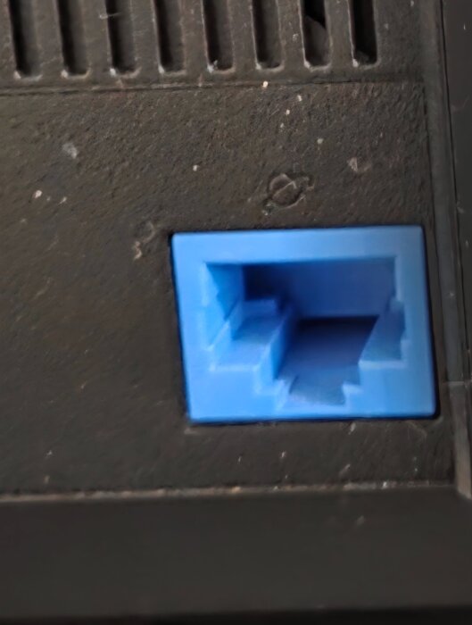 BlÄ RJ45 ethernetport pÄ en svart yta.